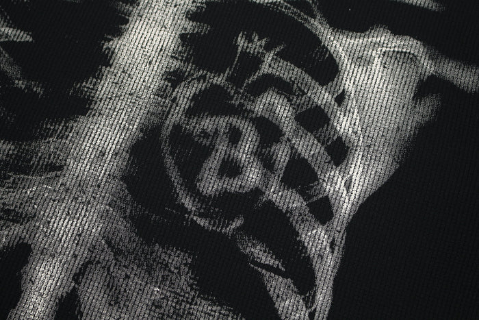 Close-up of black streetwear tee with large white skeleton ribcage graphic print on textured fabric