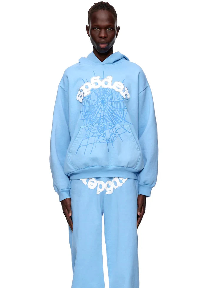 Wearing the Sp5der Hoodie – Sky Blue 440GSM Heavyweight Chenille Logo Spider-Web Streetwear Pullover and matching light blue sweatpants creates a bold streetwear look.