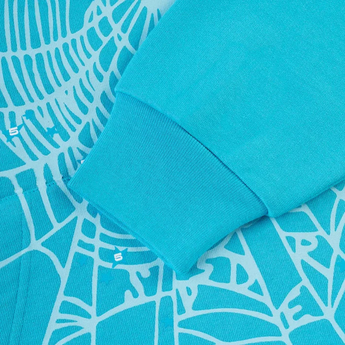 A close-up of the Sp5der “Nevermind the Spider” Hoodie in Sky Blue (440GSM heavyweight cotton fleece), showcasing its sleeve on fabric with an abstract white line pattern and small white S letters integrated into the design.