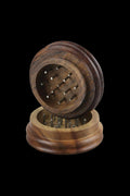 Angled close-up of the open Wood Grinder - Ben Franklin showing its carved wooden halves and metal grinding pins against a black background