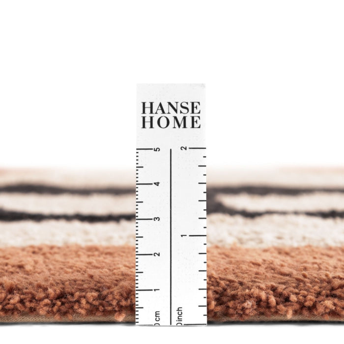 Close-up of a rug with a ruler displaying measurements, branded 'HANSE HOME'.