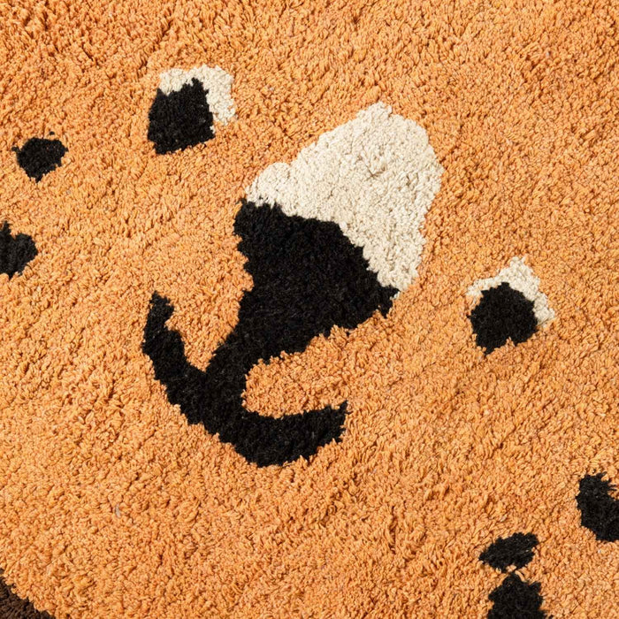 Close-up of a doormat with a smiling face design on a brown background