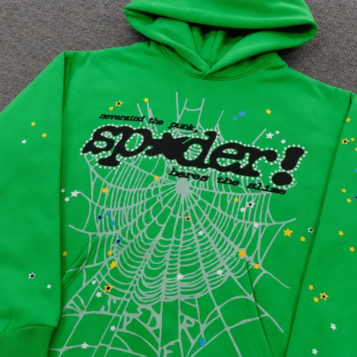 The Sp5der Neon Green Spiderweb Graphic Pullover Hoodie features a bold spiderweb design, colorful stars, and black "spider!" and "reversing the punk" text, shown laid flat on a gray surface.