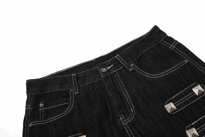 Close-up of black denim waistband and front pocket with studded strap detail