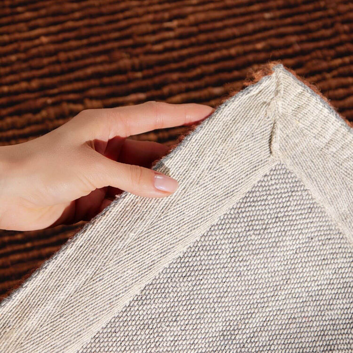 Hand touching a textured gray fabric against a brown background