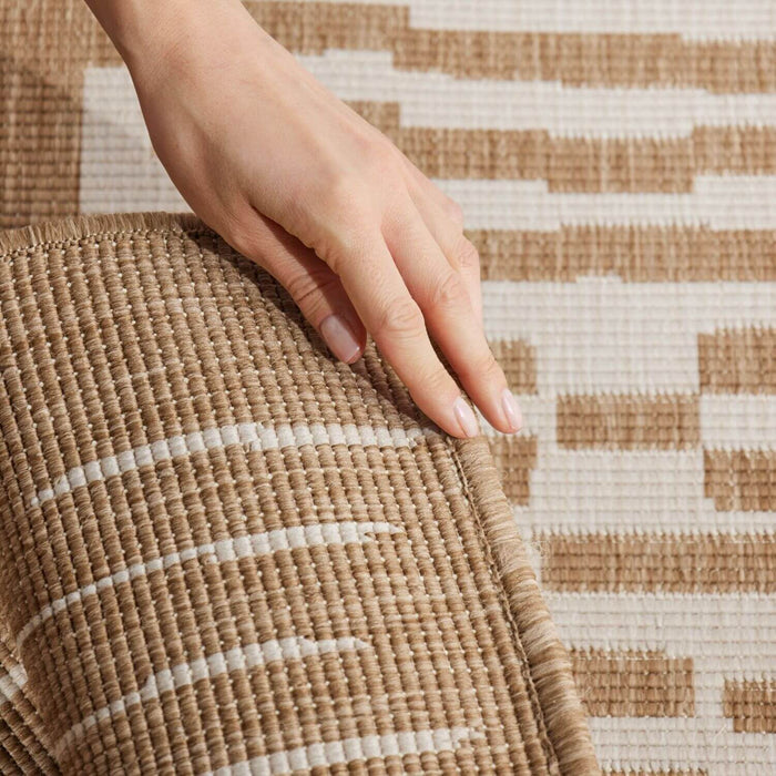 Hand touching a woven mat with a geometric pattern