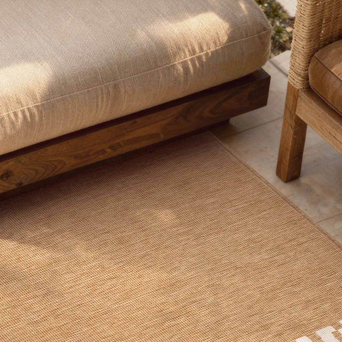 Beige outdoor rug with wooden furniture in the background