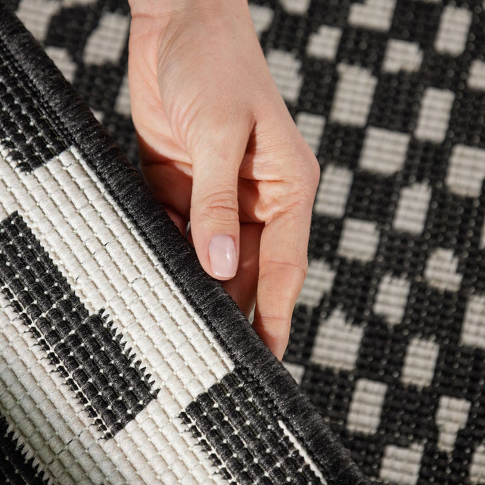 Hand touching a black and white checkered rug