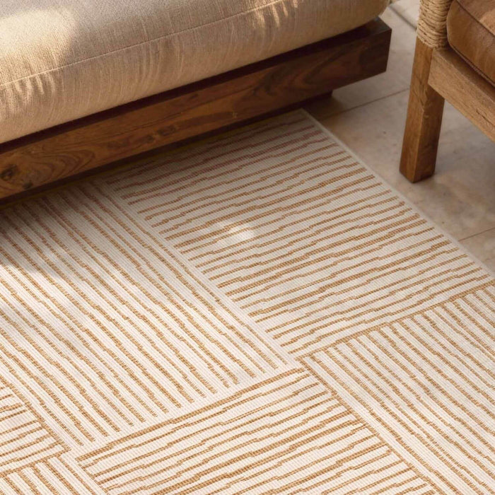 Beige patterned rug on a wooden floor with a sofa and chair in the background.