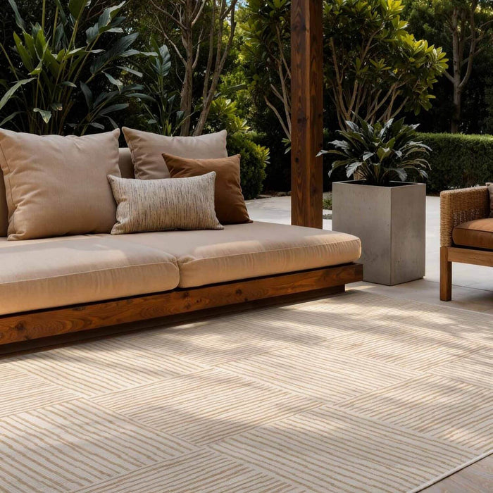 Outdoor seating area with a beige sofa and cushions on a wooden deck.