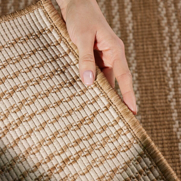 Close-up of a hand touching a textured brown and beige rug