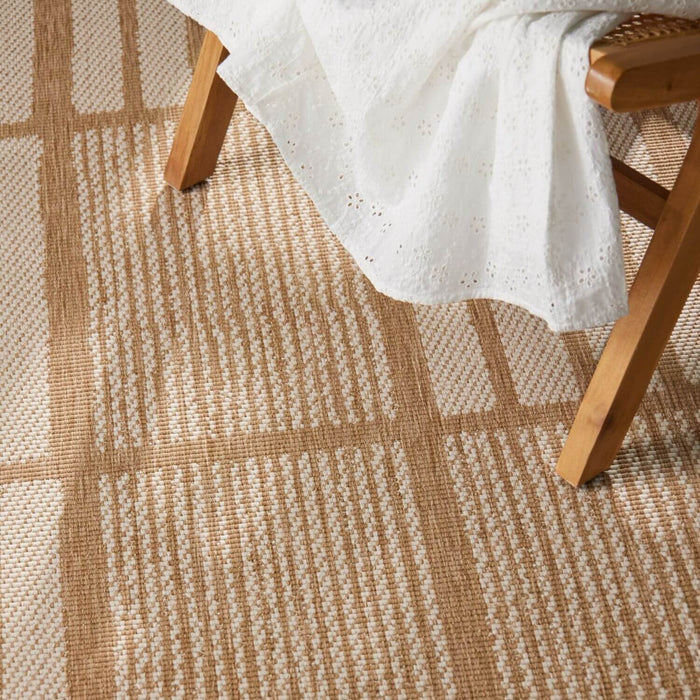 Close-up of a brown and beige checkered rug with a wooden chair and white fabric.