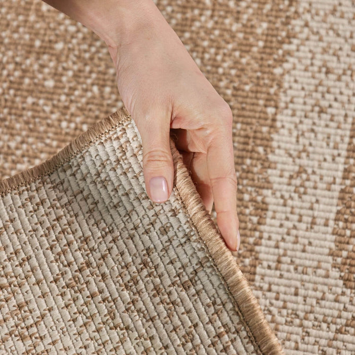 Hand pulling a beige woven rug