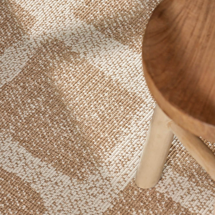 Close-up of a textured beige and brown carpet with a wooden chair leg.