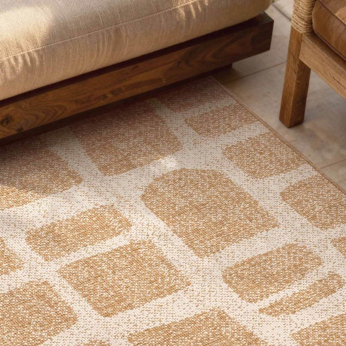 Patterned beige rug on a wooden floor with a sofa and chair in the background