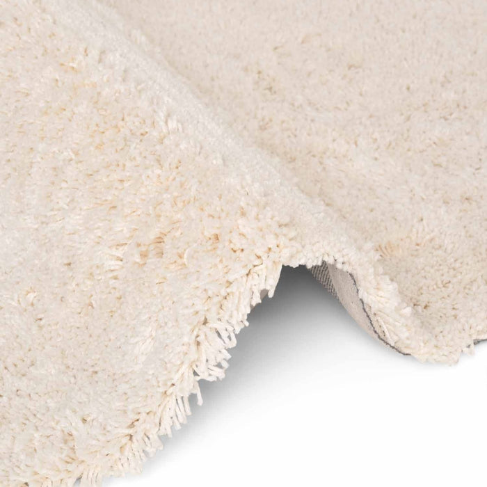 Close-up of a textured beige rug corner on a white background