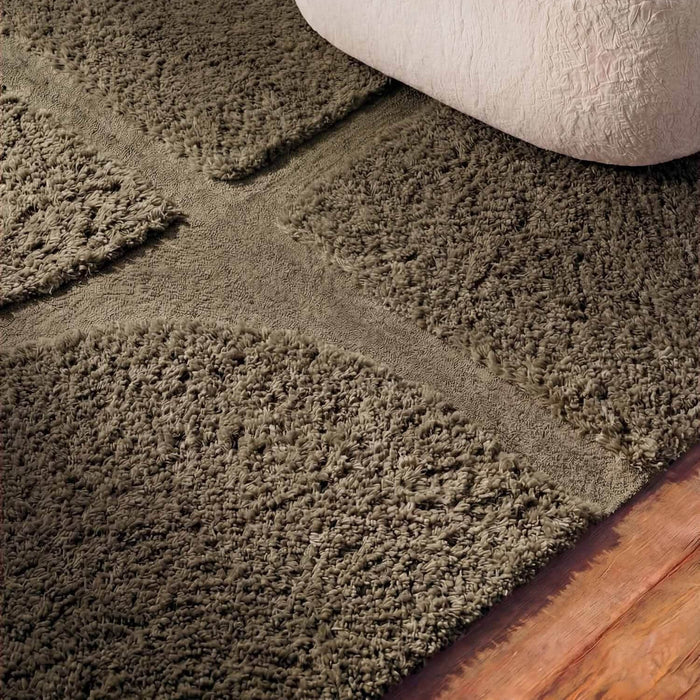 Close-up of a textured brown carpet with a wooden floor.