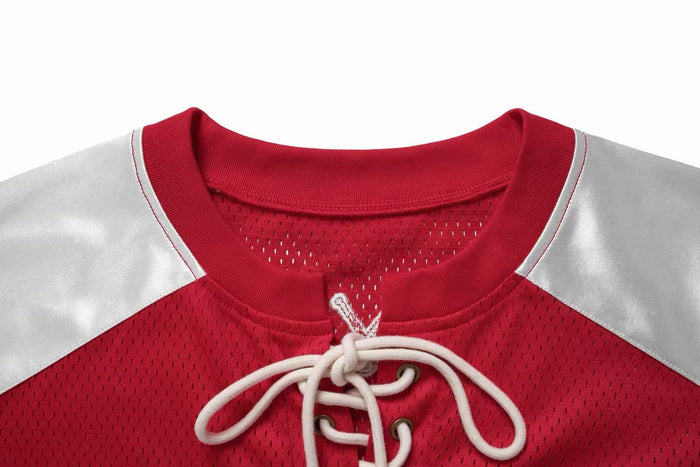 Close-up of a red mesh hockey jersey T-shirt with white shoulders, lace-up neckline, and ribbed collar detalles