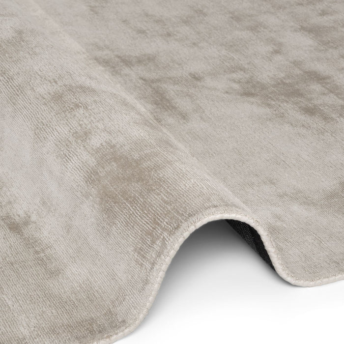 Close-up of a textured gray rug corner on a white background