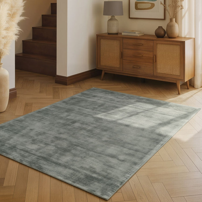 Gray rug on a wooden floor with a wooden sideboard in the background