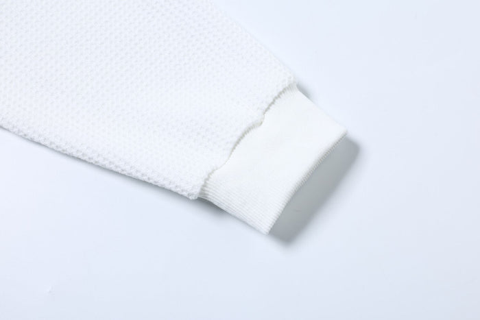 Close-up of white long sleeve cuff with ribbed trim and waffle knit sleeve