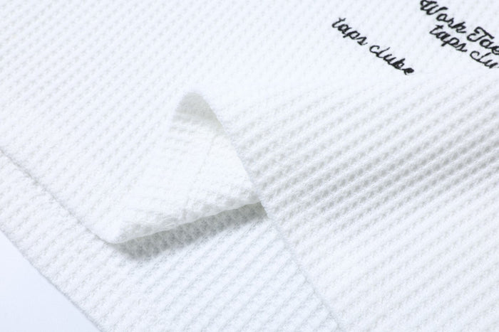 Close-up of white waffle knit fabric with printed black script detail