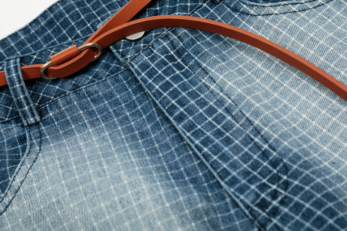 Close-up of belt buckle and faded grid denim fabric on the shorts