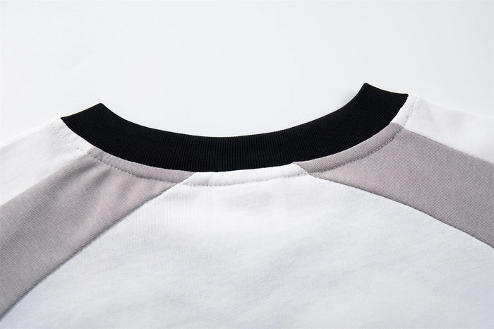 Close-up of a white and gray raglan streetwear tee with a black ribbed crew neckline and stitched shoulder seams