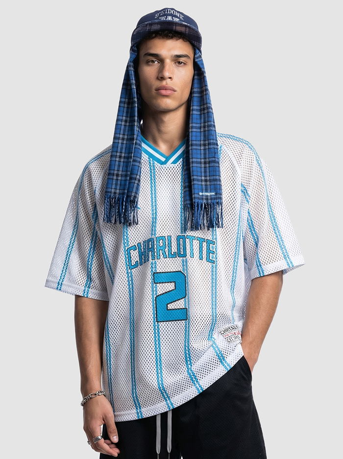 Model wearing a white mesh Charlotte jersey shirt with blue stripes and number 2, paired with a blue plaid scarf and cap