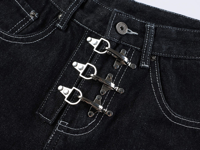 Close-up of the triple silver buckle closures on dark wash denim shorts