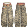 Front and back view of wide-leg camo denim pants with printed plaid waistband, star graphics, badge patches, and decorative c