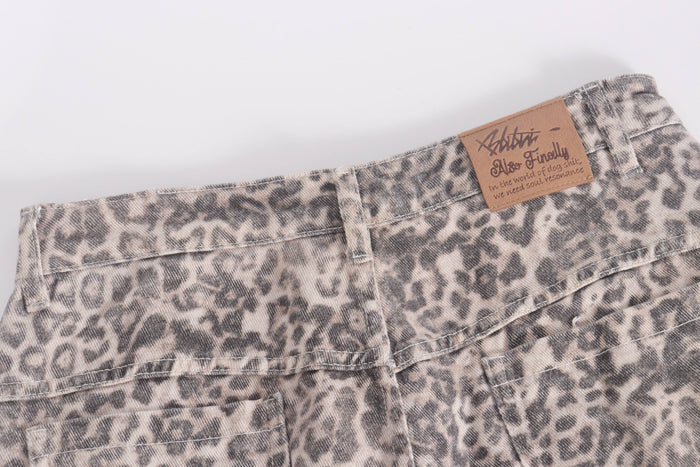 Back waistband close-up with brown logo patch on leopard print denim