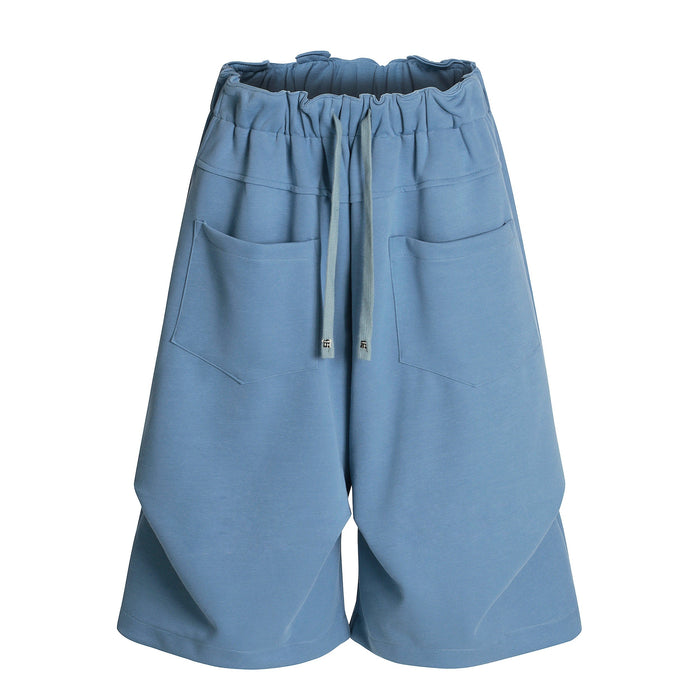 Blue wide-leg shorts front view with elastic waist, drawstring, and patch pockets